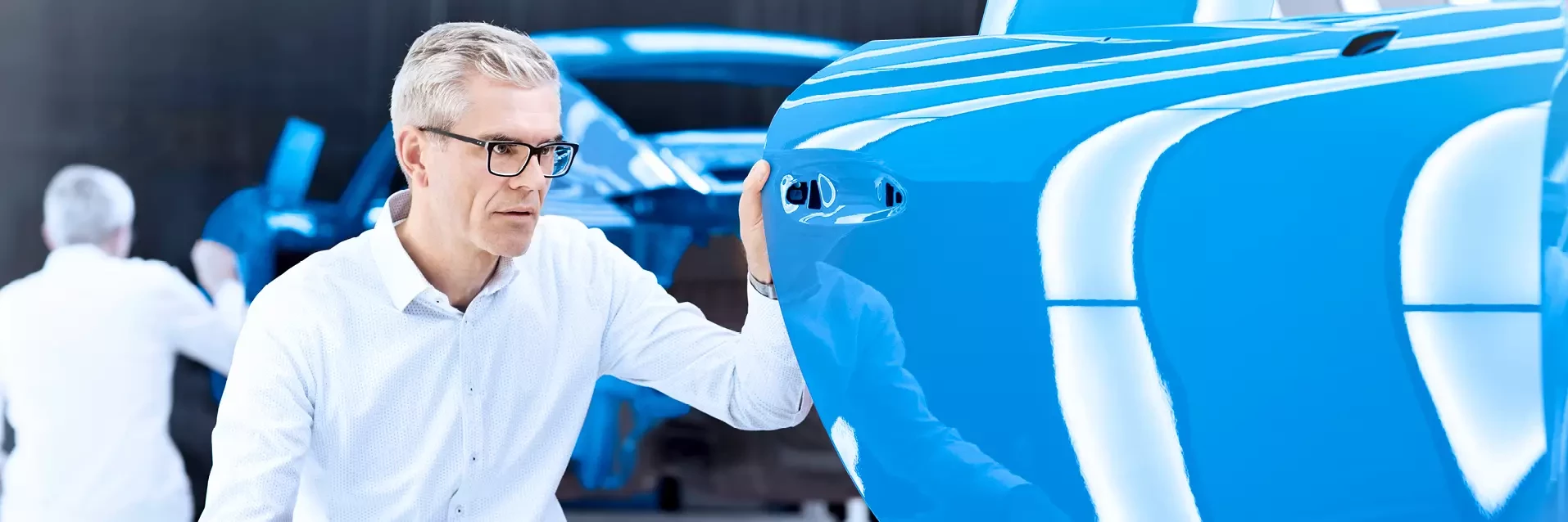 A man checks the quality of the paint on a car after it has been painted