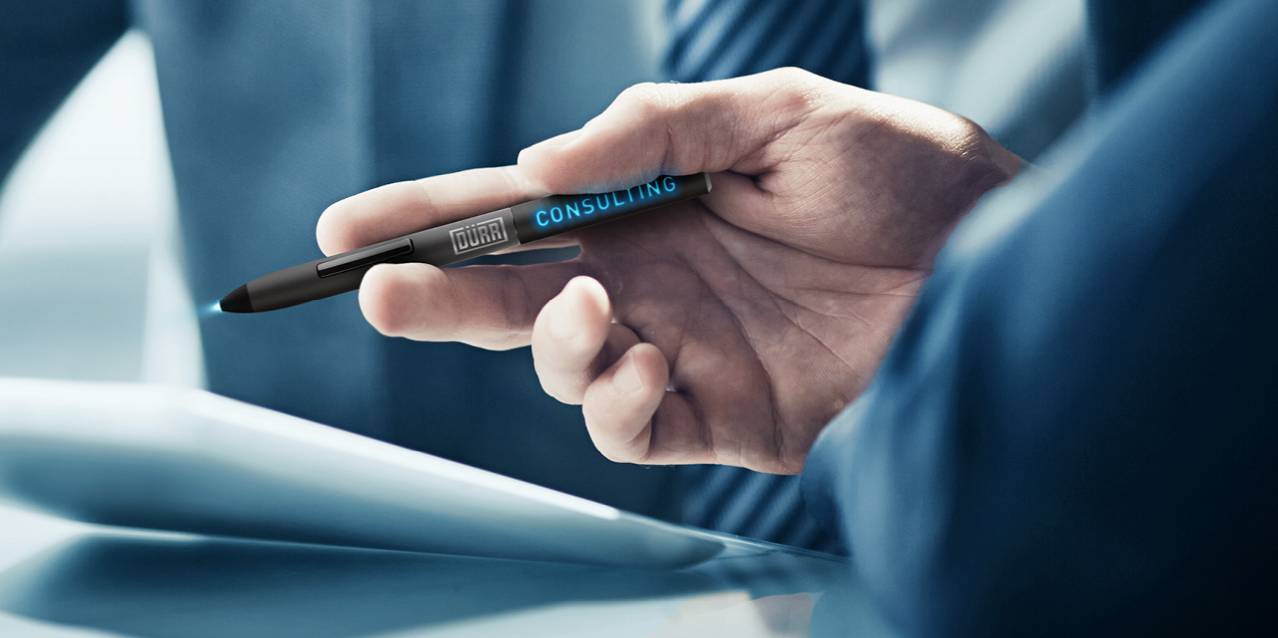 duerr-consulting-expertsDürr Consulting's consulting services represented by a hand holding a tablet pen with the Dürr Consulting logo illuminated. 